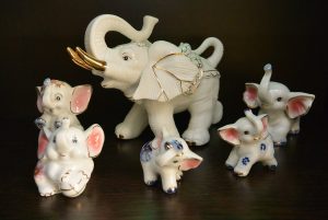 Un grupo de elefantes de porcelana, uno adulto y otros pequeños