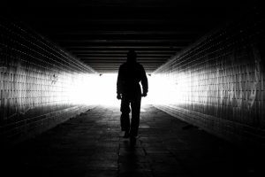 En un túnel oscuro en blanco y negro se ve la figura de un hombre andando